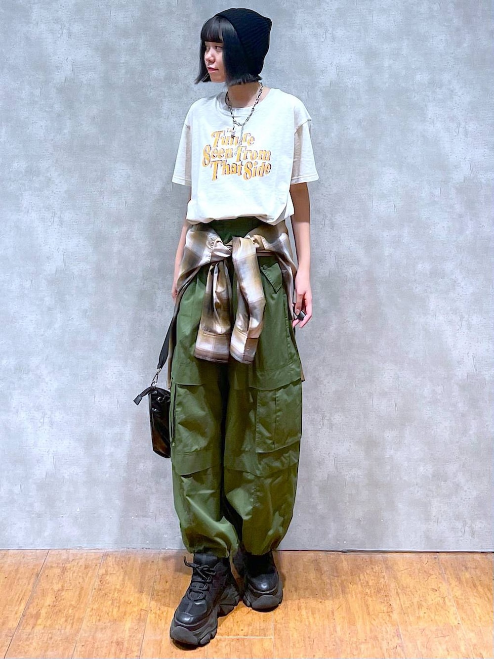 ブラック系のスニーカー、グリーン系のその他パンツ、ベージュ系のTシャツ/カットソーを着用したレディースの夏コーディネートの5枚目の写真