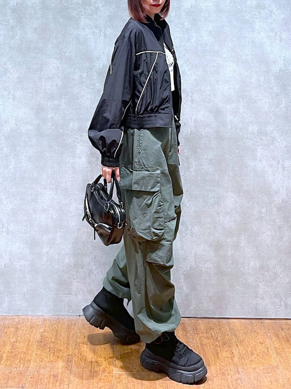 ブラック系のブルゾン、ホワイト系のTシャツ/カットソー、グリーン系のカーゴパンツを着用したレディースの春コーディネートの5枚目の写真