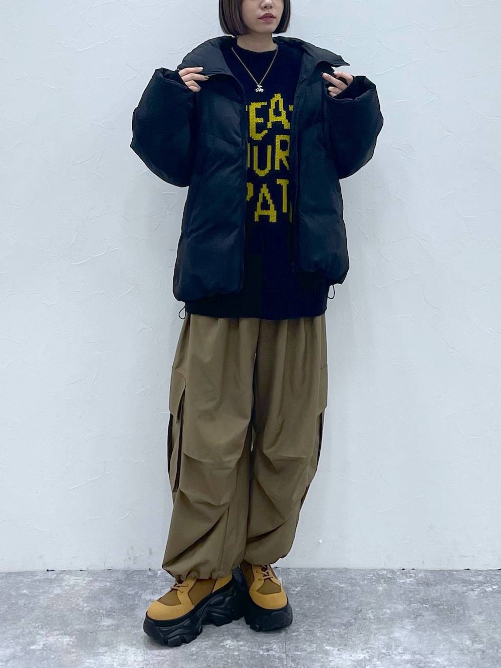 ブラウン系のブーツ、ベージュ系のカーゴパンツ、ブラック系のブルゾンを着用したレディースの秋コーディネートの7枚目の写真