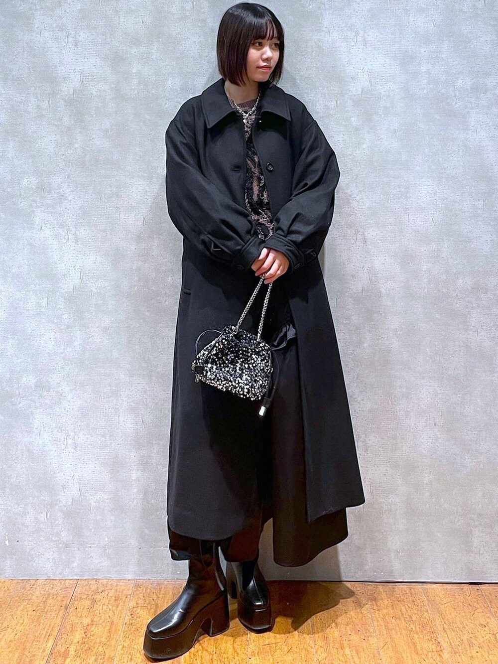 ブラック系のチェスターコート、ブラック系のブーツ、ブラウン系のニット/セーターを着用したレディースの冬コーディネートの4枚目の写真