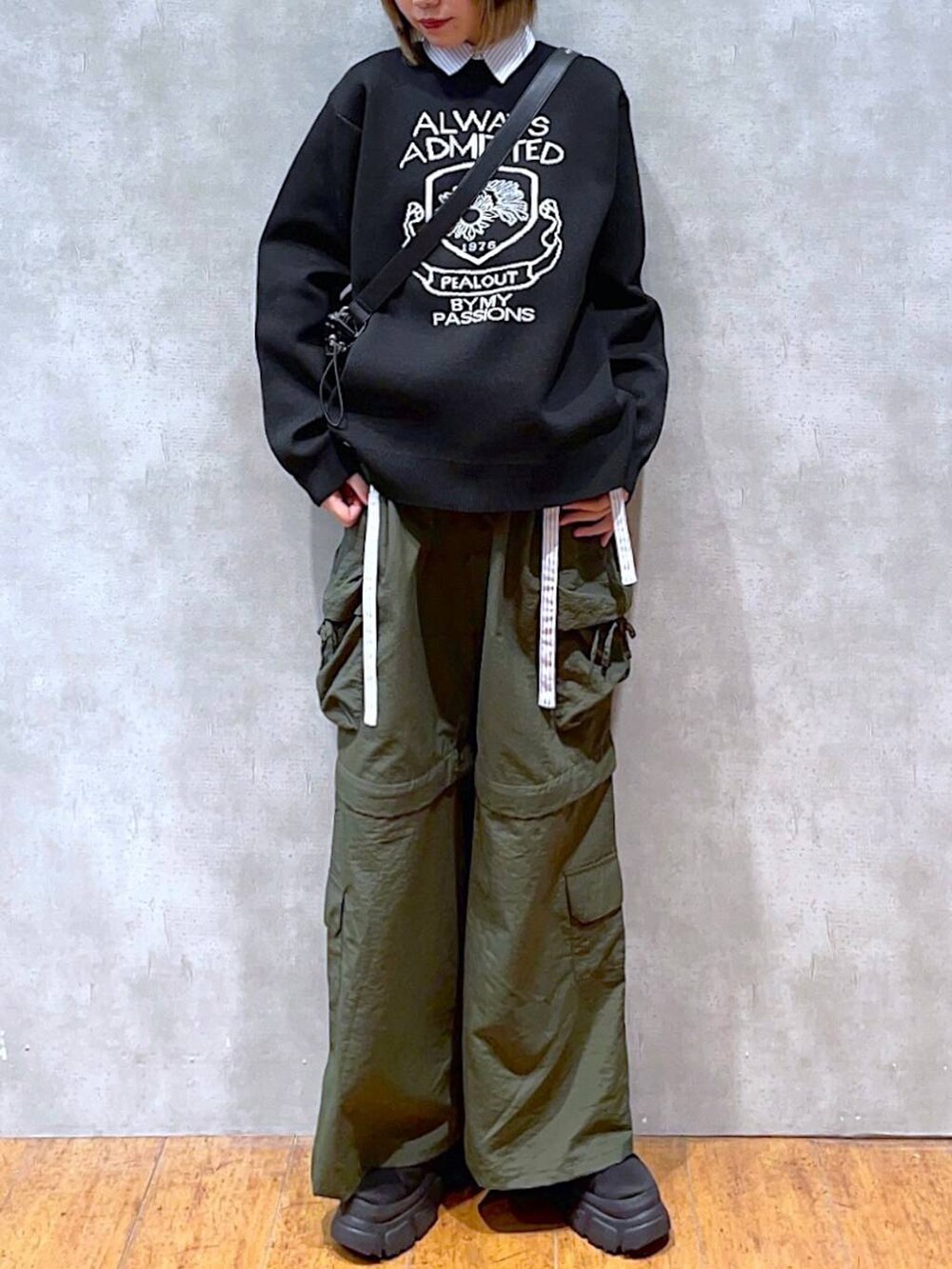 ブラック系のショルダーバッグ、ブラック系のニット/セーター、ブルー系のシャツ/ブラウスを着用したレディースの冬コーディネートの2枚目の写真