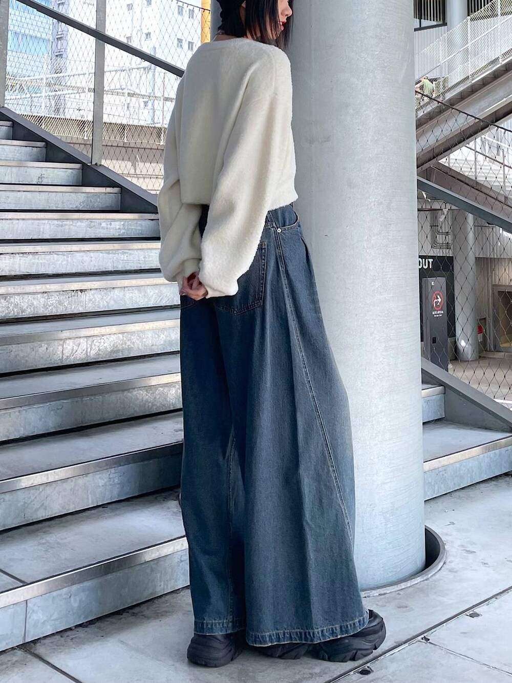 ブラック系のスニーカー、ブルー系のデニムパンツ、ホワイト系のニット/セーターを着用したレディースの秋コーディネートの4枚目の写真