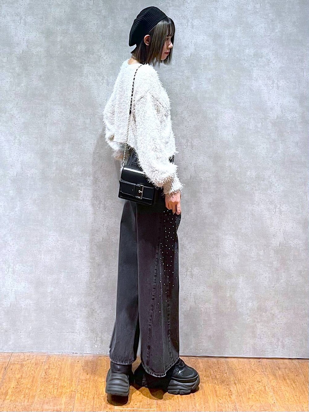 ブラック系のスニーカー、ブラック系のデニムパンツ、ブラック系のショルダーバッグを着用したレディースの秋コーディネートの5枚目の写真