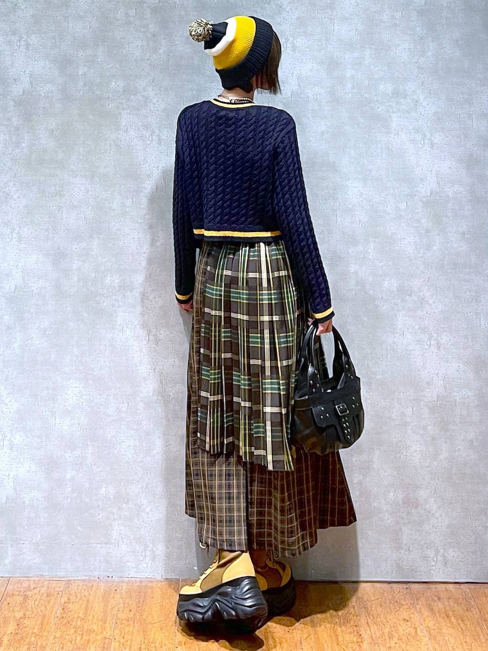 ブラウン系のブーツ、イエロー系のスカート、ブラック系のハンドバッグを着用したレディースの秋コーディネートの4枚目の写真