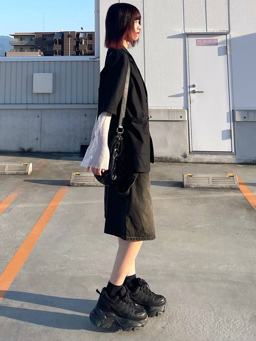 ブラック系のショルダーバッグ、ブラック系のスニーカー、ホワイト系のTシャツ/カットソーを着用したレディースの春コーディネートの7枚目の写真