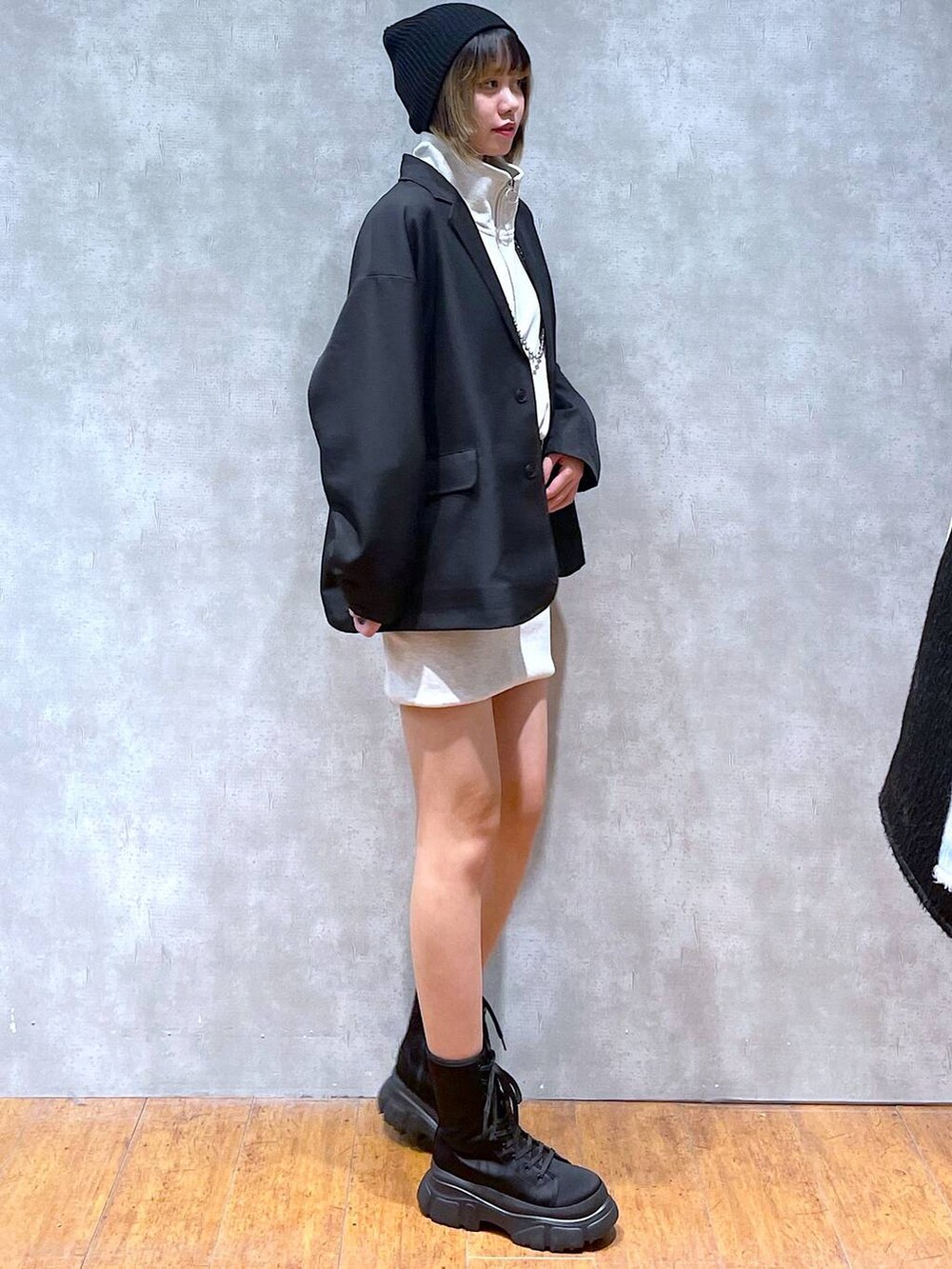 ブラック系のテーラードジャケット、ベージュ系のワンピース、ブラック系のブーツを着用したレディースの冬コーディネートの2枚目の写真