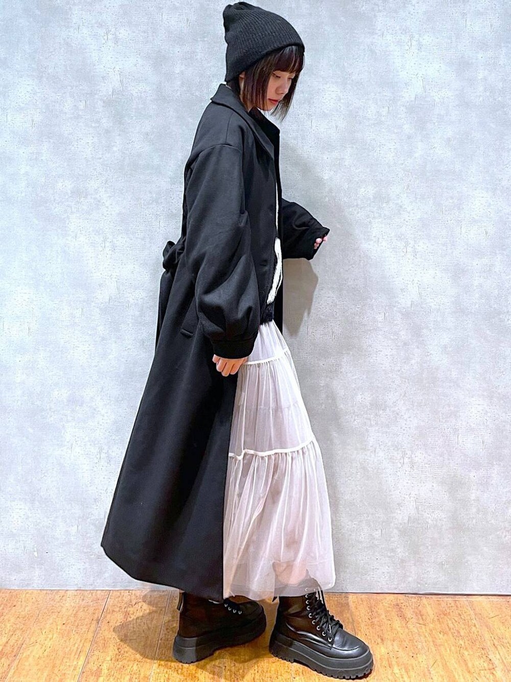 ブラック系のブーツ、ブラック系のチェスターコート、ブラック系のニット/セーターを着用したレディースの冬コーディネートの2枚目の写真