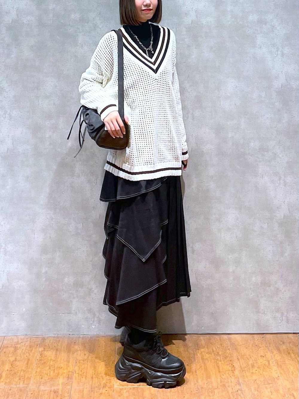 ブラック系のスニーカー、ブラック系のニット/セーター、ブラック系のショルダーバッグを着用したレディースの秋コーディネートの7枚目の写真