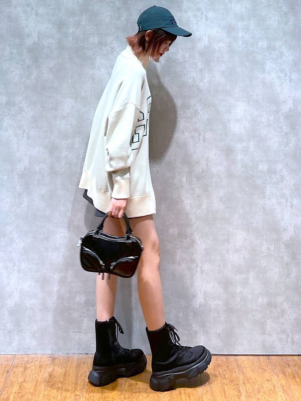 ベージュ系のニット/セーター、グレー系のその他パンツ、ブラック系のブーツを着用したレディースの春コーディネートの7枚目の写真