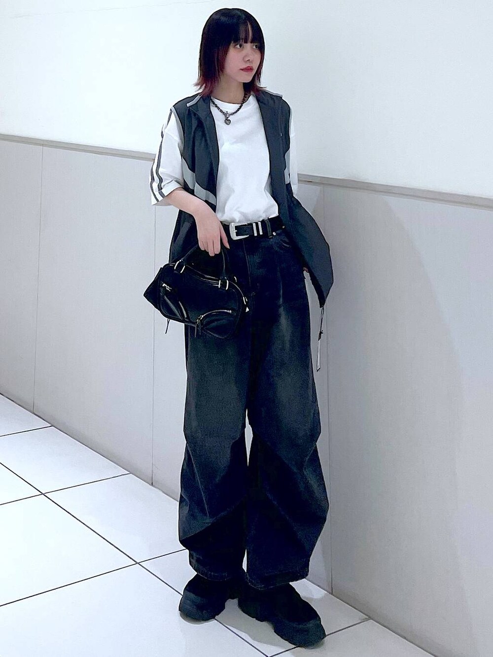 グレー系のベスト、ブラック系のデニムパンツ、ホワイト系のTシャツ/カットソーを着用したレディースの春コーディネートの2枚目の写真