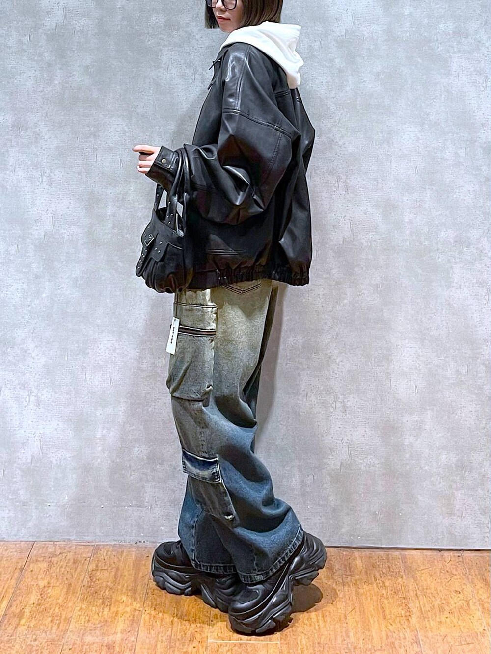 ブラック系のスニーカー、ブラック系のブルゾン、ブルー系のデニムパンツを着用したレディースの秋コーディネートの3枚目の写真