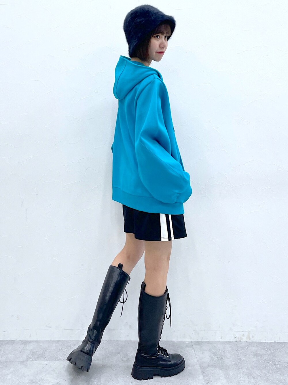 ブルー系のパーカー、ブラック系のスカート、ブラック系のブーツを着用したレディースの秋コーディネートの2枚目の写真