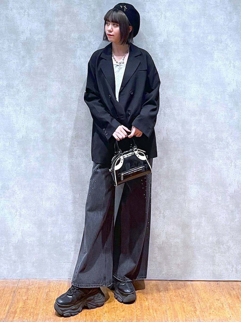 ブラック系のスニーカー、ブラック系のデニムパンツ、ブラック系のショルダーバッグを着用したレディースの秋コーディネートの6枚目の写真