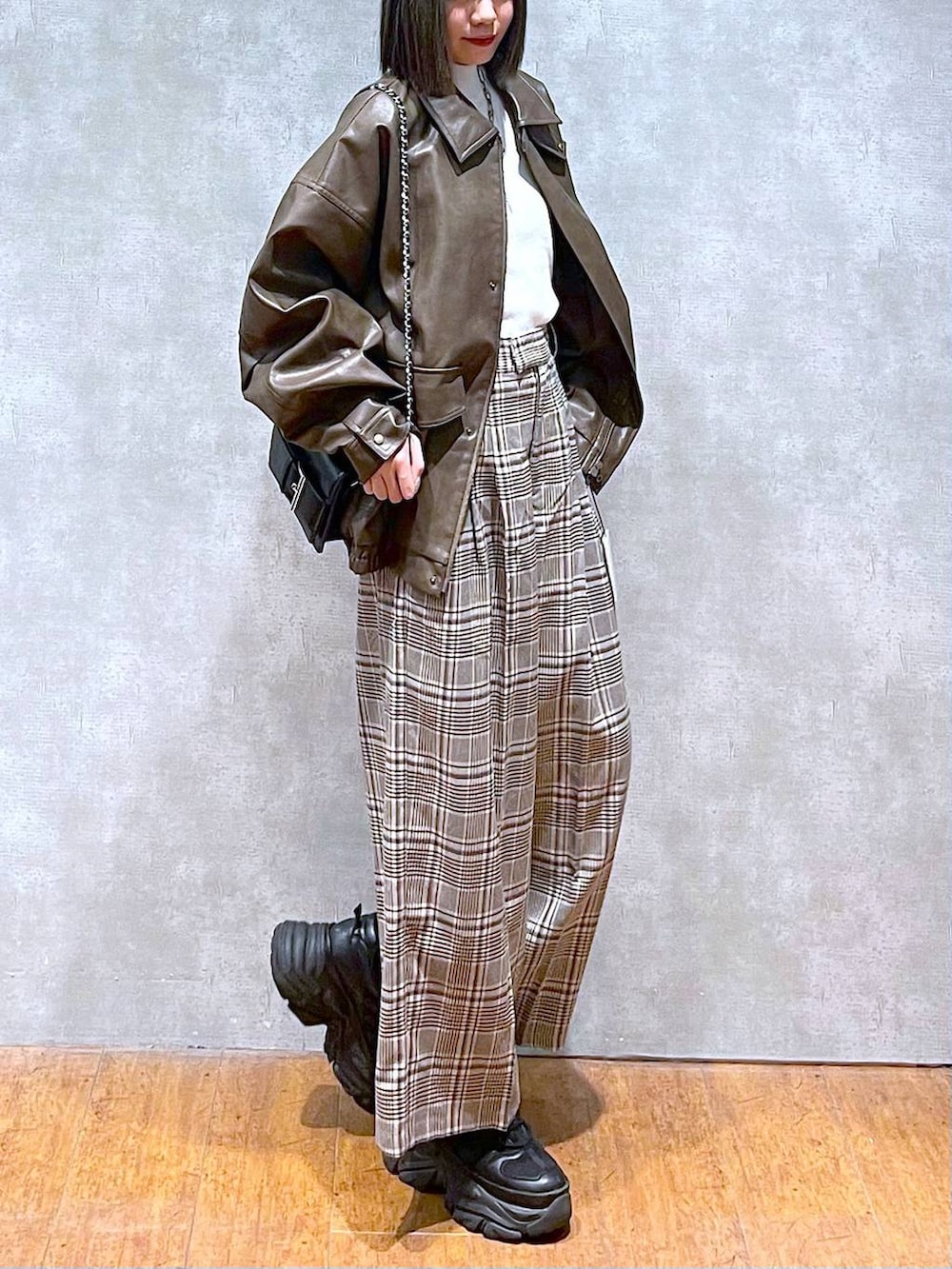 ブラック系のスニーカー、ホワイト系のニット/セーター、ベージュ系のスラックスを着用したレディースの秋コーディネートの6枚目の写真