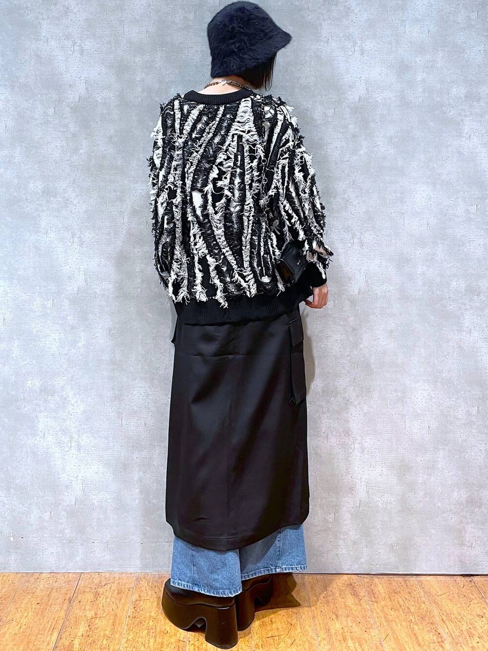 ブラック系のスカート、ブルー系のデニムパンツ、ブラック系のブーツを着用したレディースの冬コーディネートの5枚目の写真