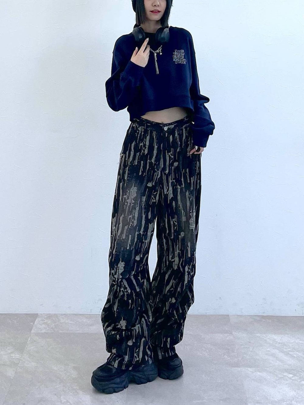 ブラック系のスニーカー、ブラック系のデニムパンツ、ホワイト系のキャミソールを着用したレディースの秋コーディネートの7枚目の写真