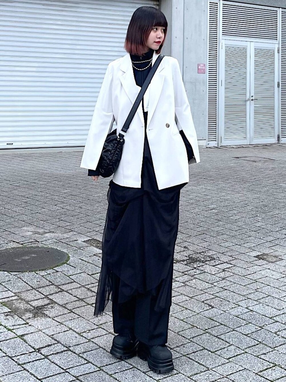 ブラック系のショルダーバッグ、ブラック系のナイロンジャケット、ブラック系のスカートを着用したレディースの春コーディネートの2枚目の写真