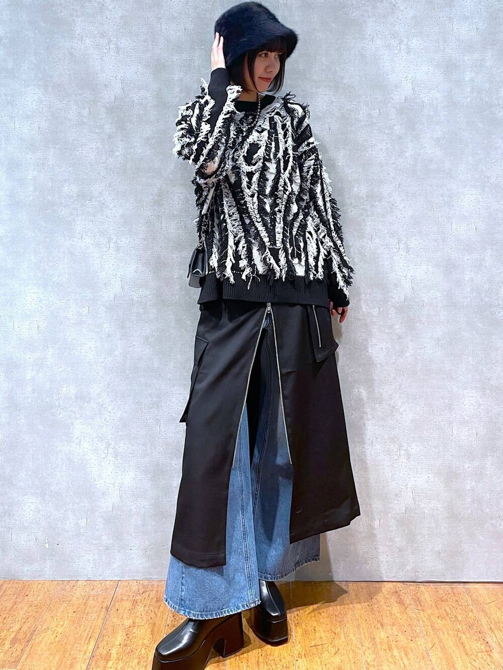 ブラック系のスカート、ブルー系のデニムパンツ、ブラック系のブーツを着用したレディースの冬コーディネートの6枚目の写真