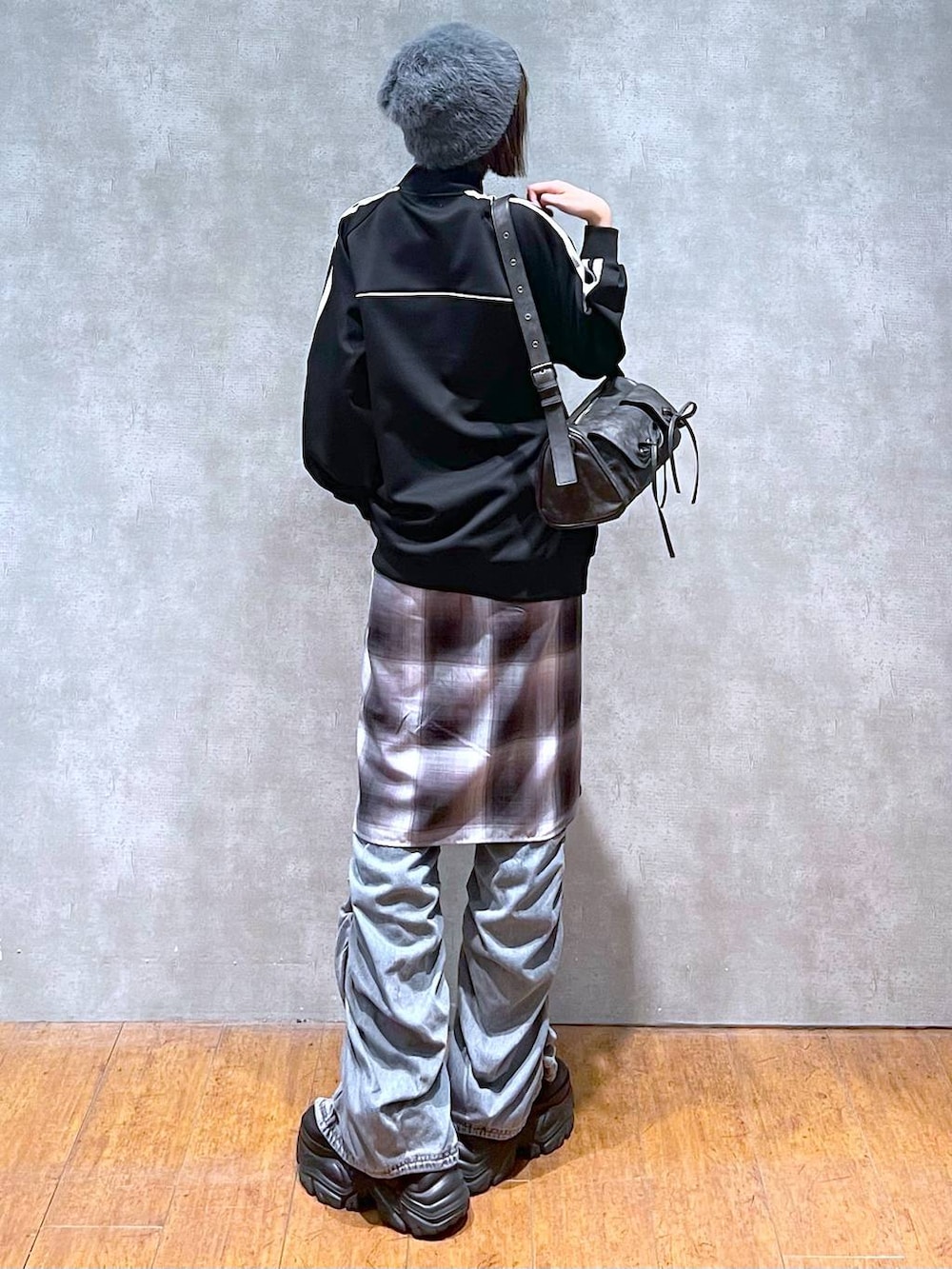 ブラック系のスニーカー、ブラック系のショルダーバッグ、ブルー系のデニムパンツを着用したレディースの秋コーディネートの5枚目の写真