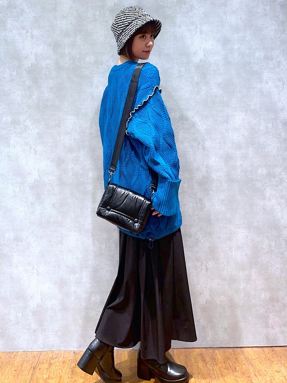 ブルー系のニット/セーター、ブラック系のショルダーバッグ、ブラック系のスカートを着用したレディースの秋コーディネートの2枚目の写真