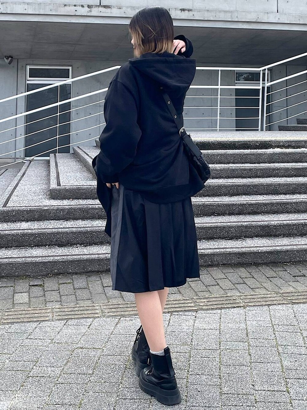 ブラック系のパーカー、ブラック系のショルダーバッグ、ブラック系のブーツを着用したレディースの冬コーディネートの8枚目の写真