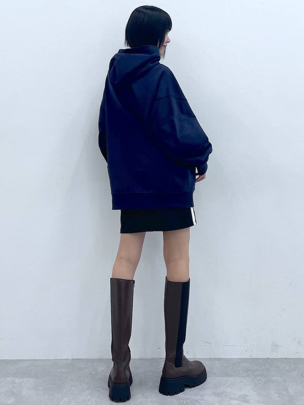 ブルー系のパーカー、ブラウン系のブーツ、ブラック系のスカートを着用したレディースの冬コーディネートの4枚目の写真