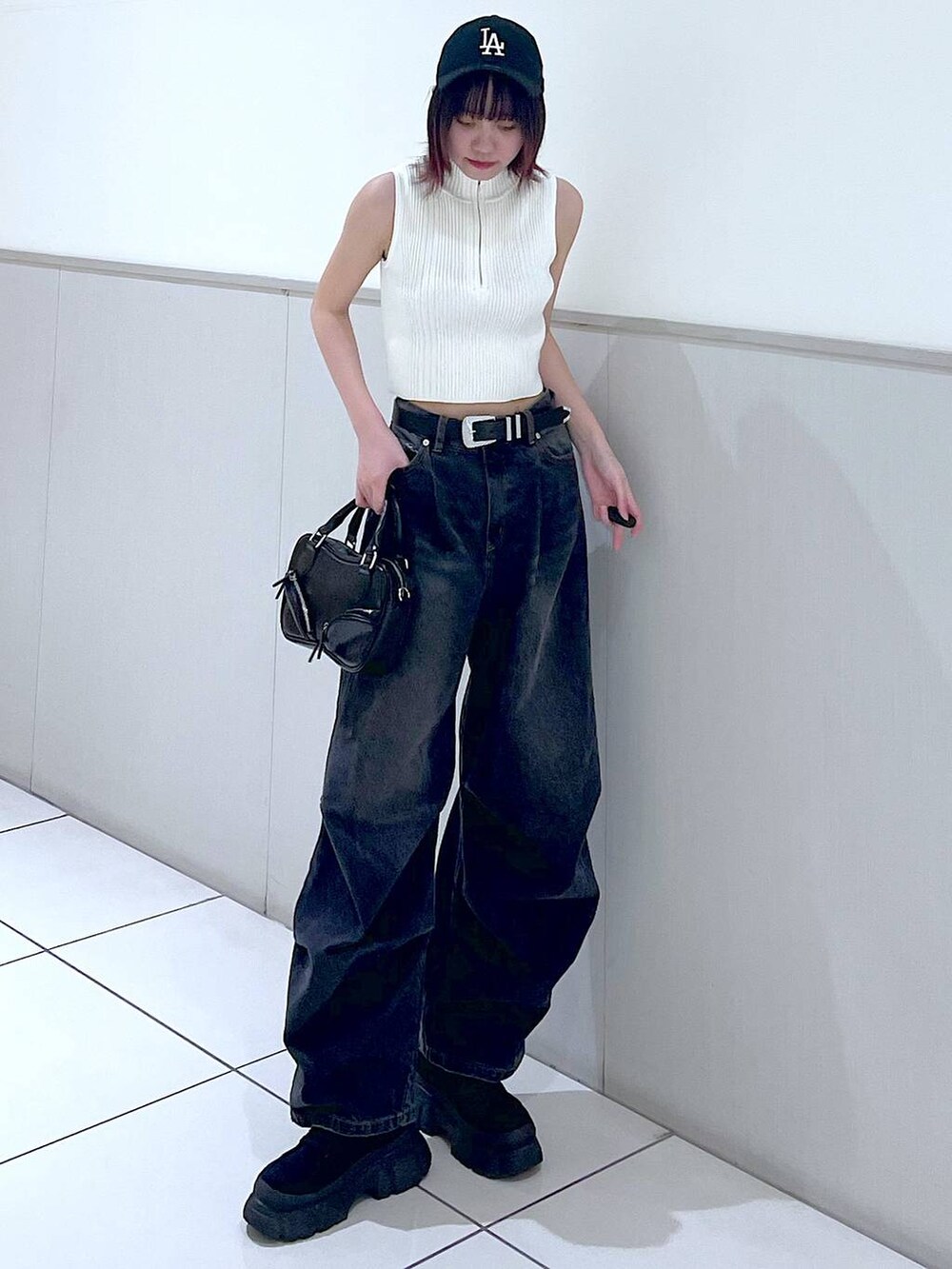 ブラック系のデニムパンツ、ホワイト系のニット/セーター、ブラック系のボストンバッグを着用したレディースの春コーディネートの2枚目の写真