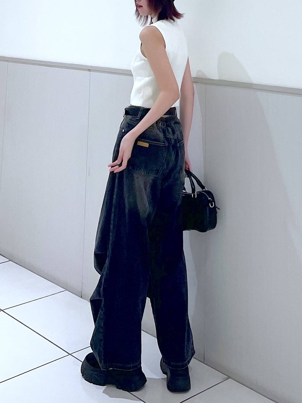 ブラック系のデニムパンツ、ホワイト系のニット/セーター、ブラック系のボストンバッグを着用したレディースの春コーディネートの7枚目の写真