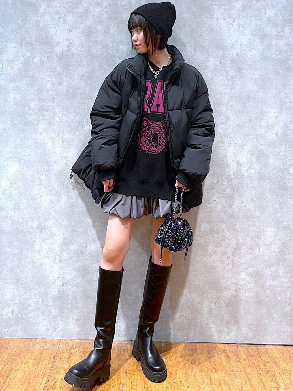 グレー系のスカート、ブラック系のブーツ、ブラック系のダウンジャケット/コートを着用したレディースの冬コーディネートの4枚目の写真