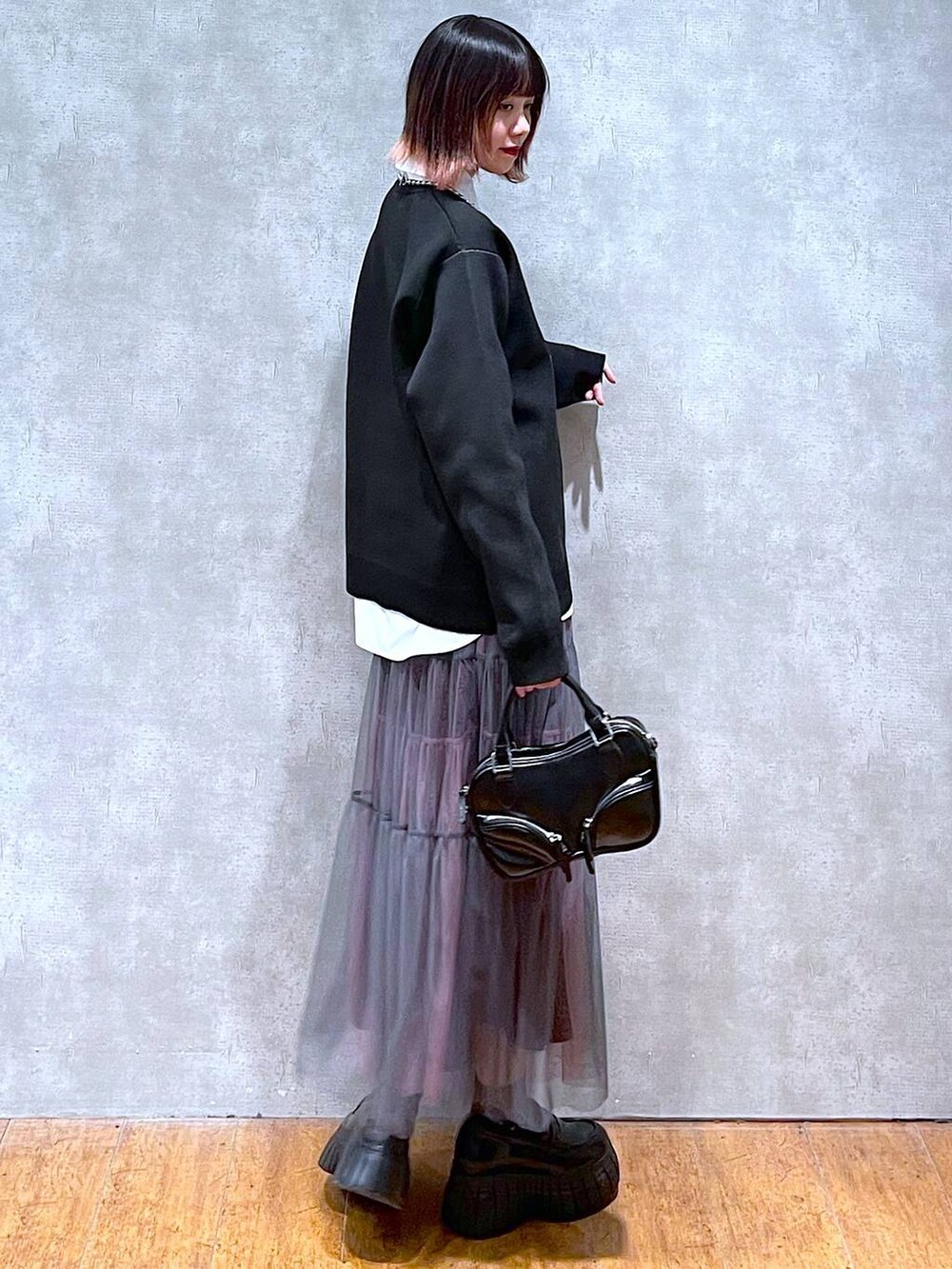 ブラック系のニット/セーター、ホワイト系のシャツ/ブラウス、グレー系のスカートを着用したレディースの春コーディネートの7枚目の写真