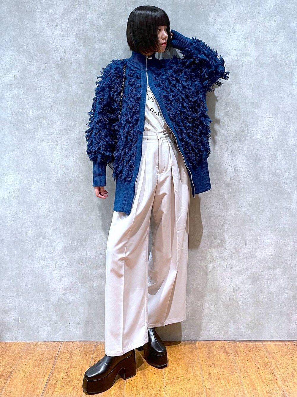 ブラック系のブーツ、ホワイト系のTシャツ/カットソー、ベージュ系のスラックスを着用したレディースの冬コーディネートの2枚目の写真