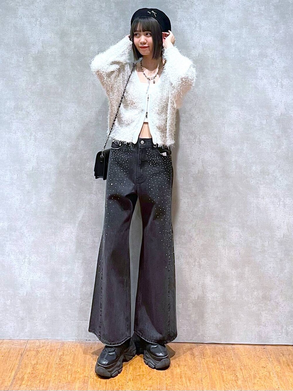 ブラック系のスニーカー、ブラック系のデニムパンツ、ブラック系のショルダーバッグを着用したレディースの秋コーディネートの2枚目の写真