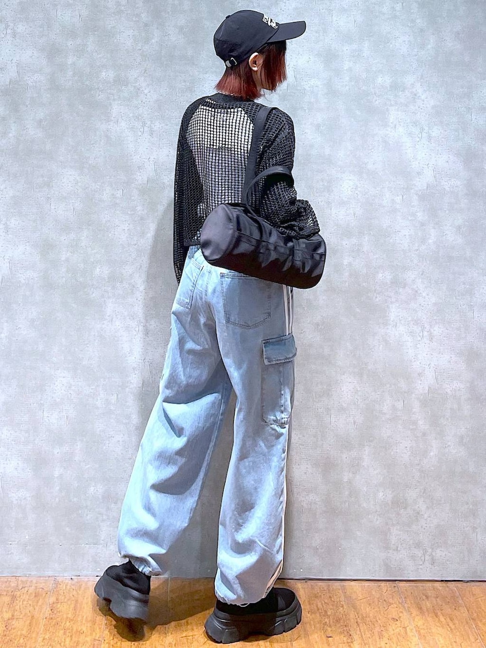 ブラック系のドラムバッグ、ホワイト系のTシャツ/カットソー、ブラック系のブーツを着用したレディースの春コーディネートの4枚目の写真