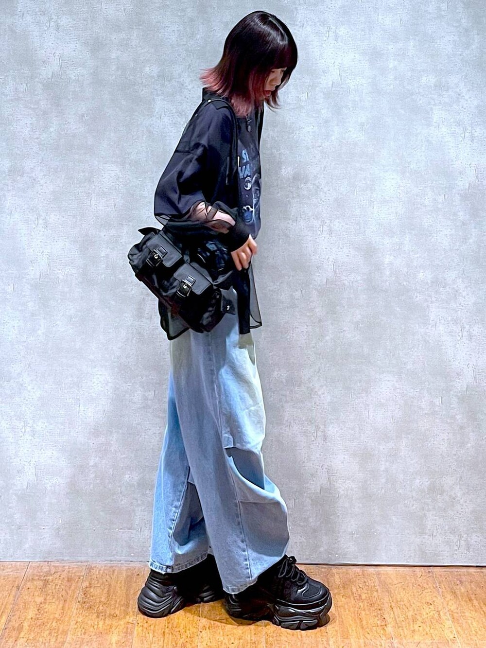 ブラック系のショルダーバッグ、ブルー系のデニムパンツ、ブラック系のスニーカーを着用したレディースの春コーディネートの6枚目の写真
