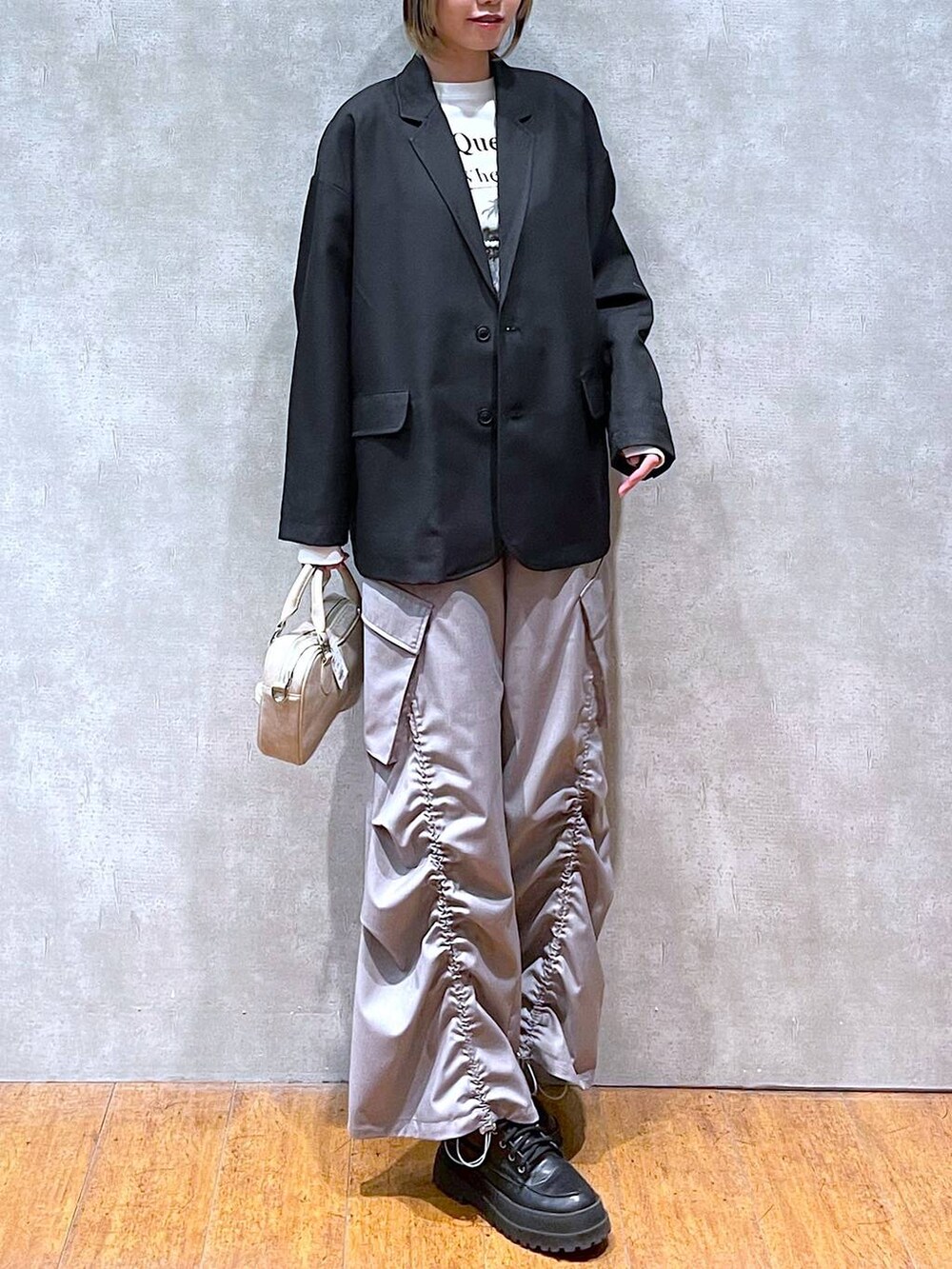 ブラック系のテーラードジャケット、ホワイト系のTシャツ/カットソー、ブラック系のブーツを着用したレディースの冬コーディネートの8枚目の写真