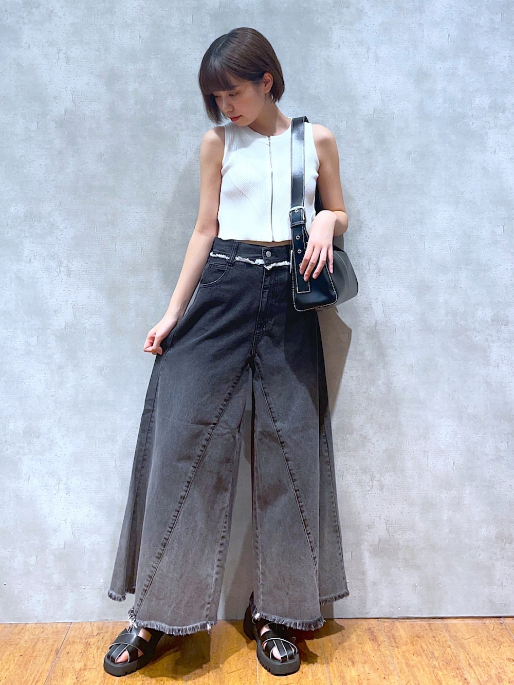 ホワイト系のタンクトップ、ブラック系のショルダーバッグ、ブラック系のデニムパンツを着用したレディースの夏コーディネートの2枚目の写真