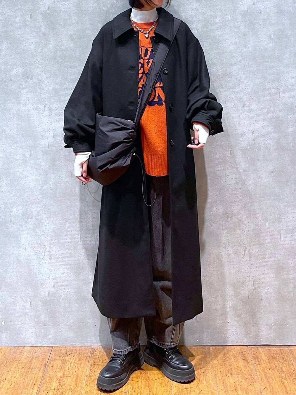 ブラック系のブーツ、ブラック系のチェスターコート、ブラック系のデニムパンツを着用したレディースの冬コーディネートの6枚目の写真