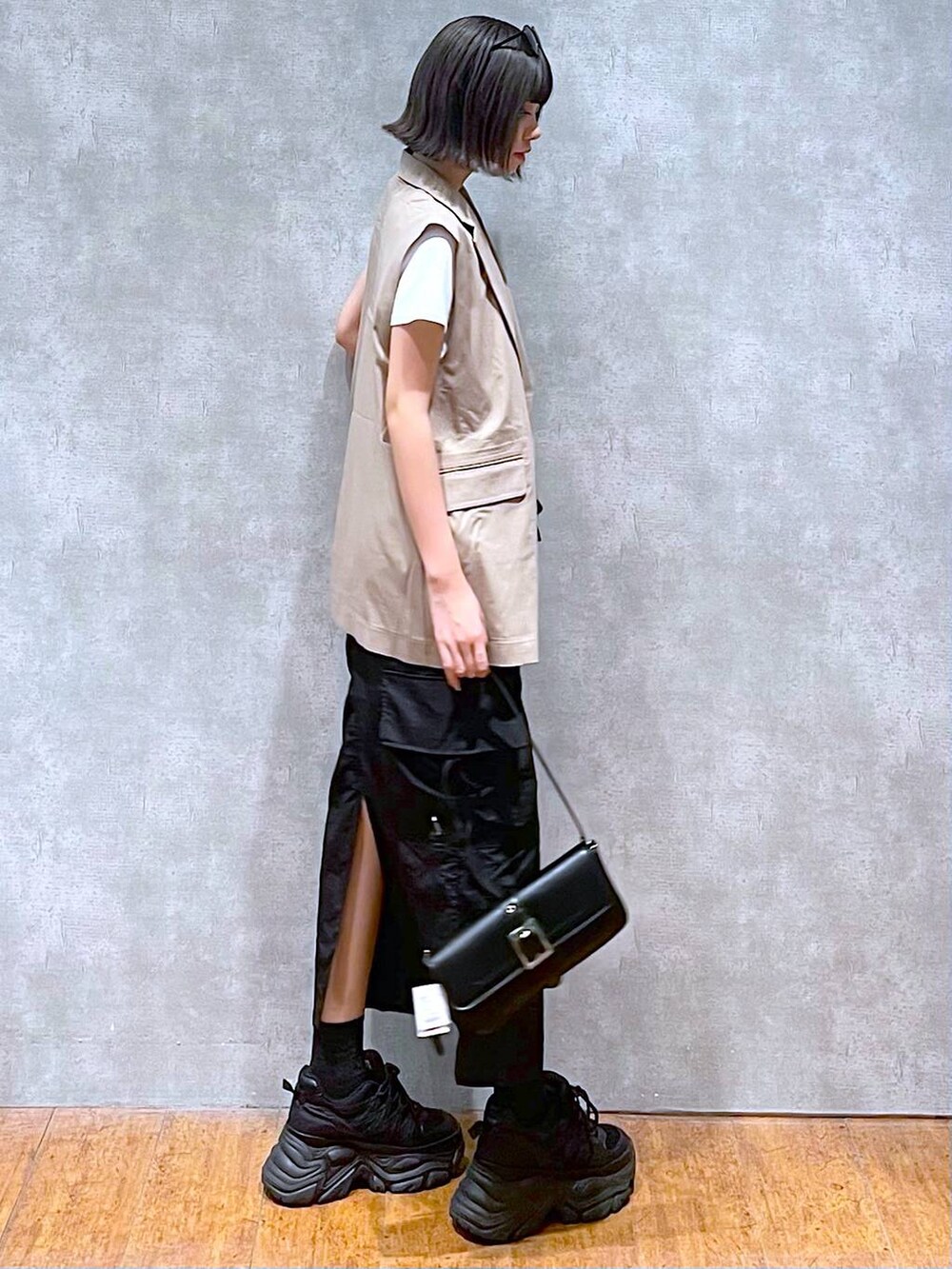 ブラック系のスニーカー、ブラック系のハンドバッグ、ホワイト系のTシャツ/カットソーを着用したレディースの夏コーディネートの7枚目の写真