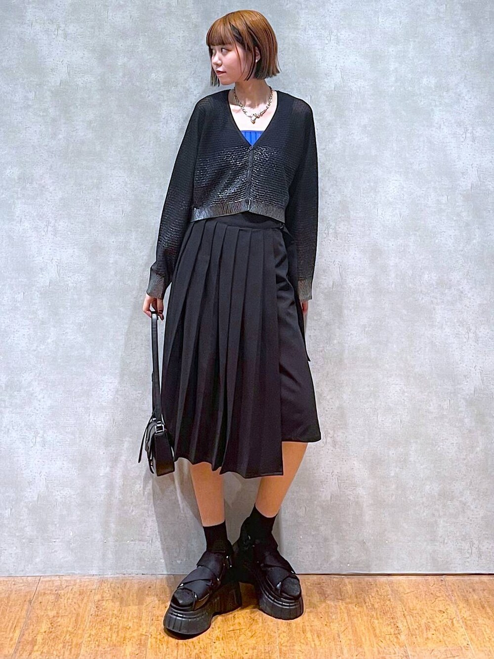 ブラック系のスニーカー、ブルー系のタンクトップ、ブラック系のスカートを着用したレディースの夏コーディネートの2枚目の写真