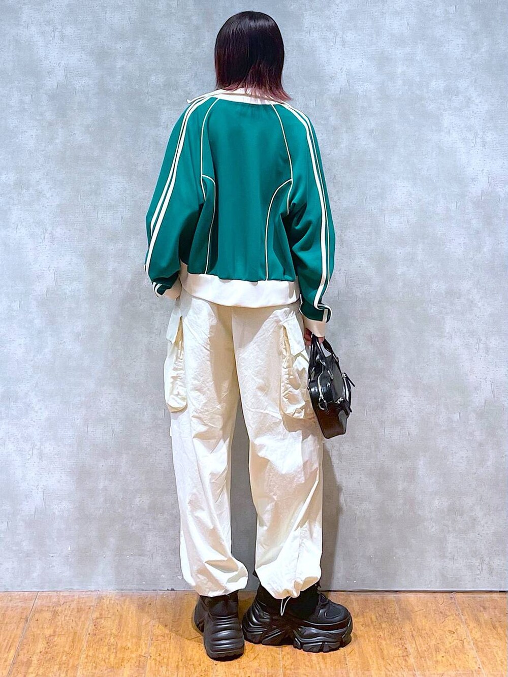 グリーン系のセットアップ、ブラック系のボストンバッグ、ホワイト系のカーゴパンツを着用したレディースの春コーディネートの7枚目の写真