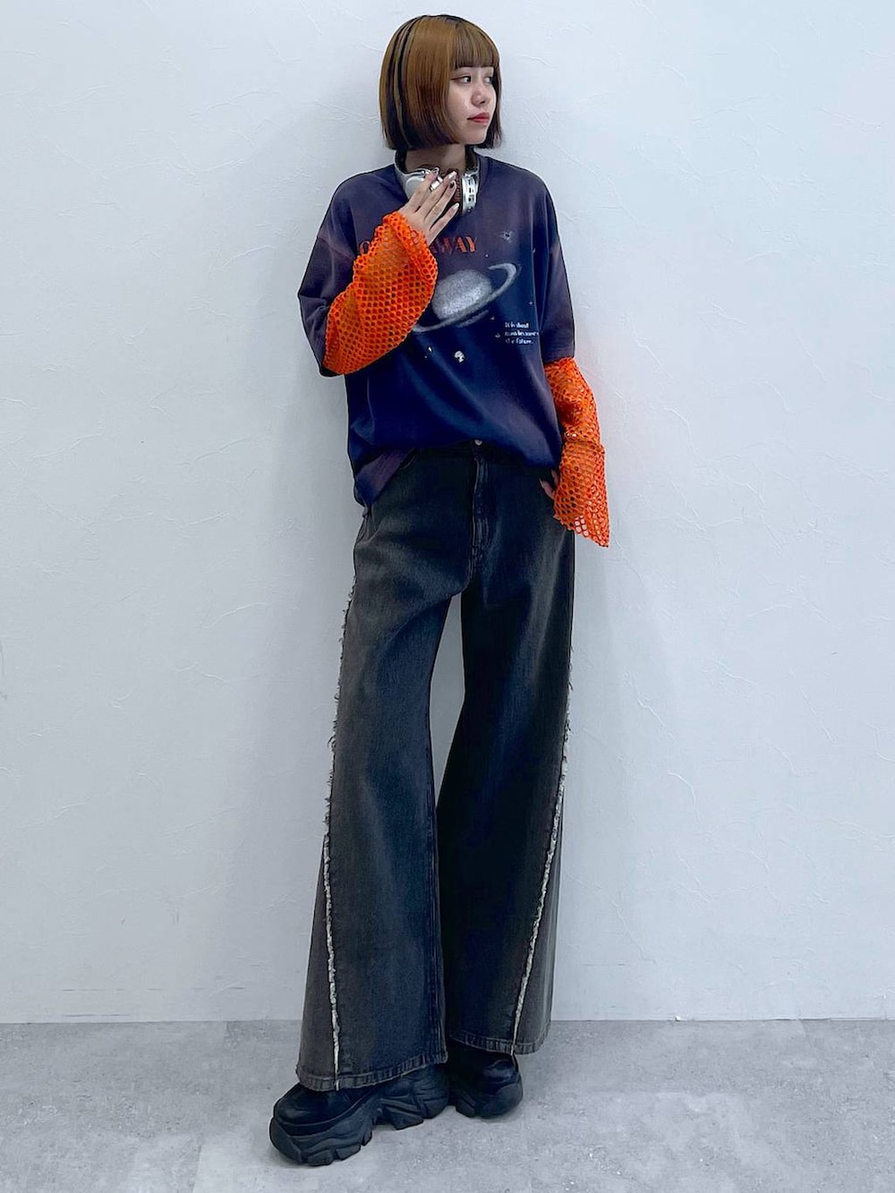 ブラック系のスニーカー、オレンジ系のTシャツ/カットソー、ブラック系のデニムパンツを着用したレディースの夏コーディネートの6枚目の写真