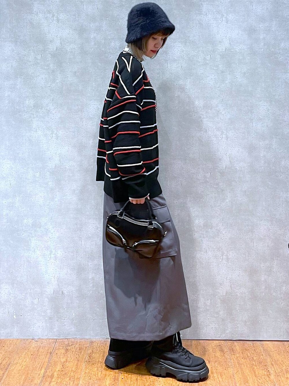 グレー系のスカート、ベージュ系のTシャツ/カットソー、ブラック系のニット/セーターを着用したレディースの冬コーディネートの3枚目の写真