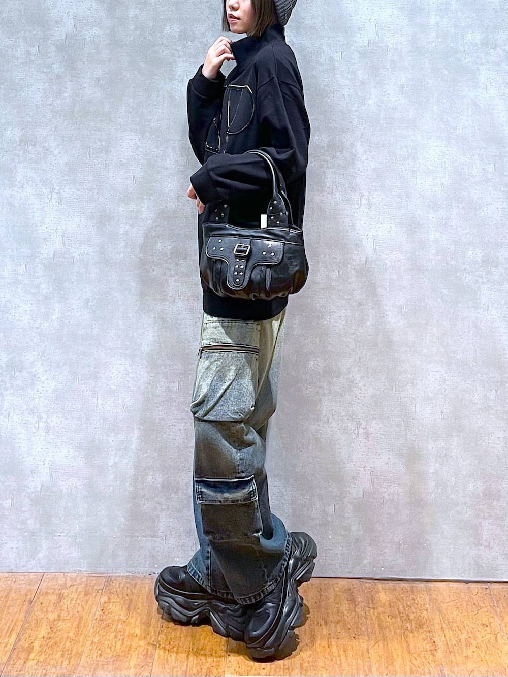 ブラック系のスニーカー、ブルー系のデニムパンツ、ブラック系のハンドバッグを着用したレディースの秋コーディネートの5枚目の写真