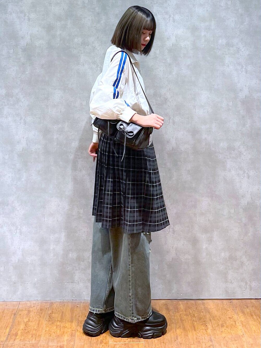 ブラック系のスニーカー、ブラック系のショルダーバッグ、ブルー系のデニムパンツを着用したレディースの秋コーディネートの6枚目の写真