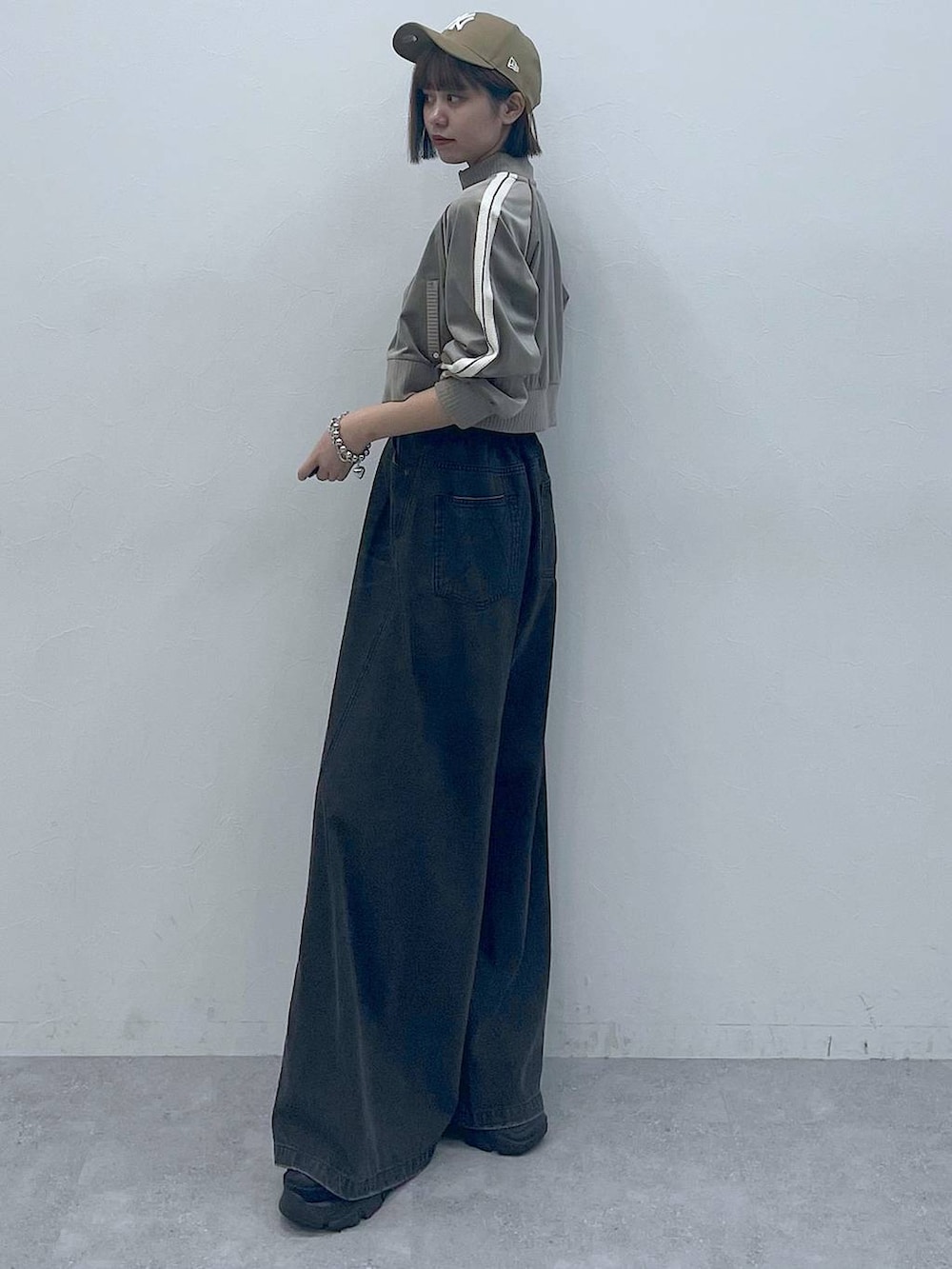 ブラック系のスニーカー、ブラック系のキャミソール、ブラック系のデニムパンツを着用したレディースの秋コーディネートの6枚目の写真