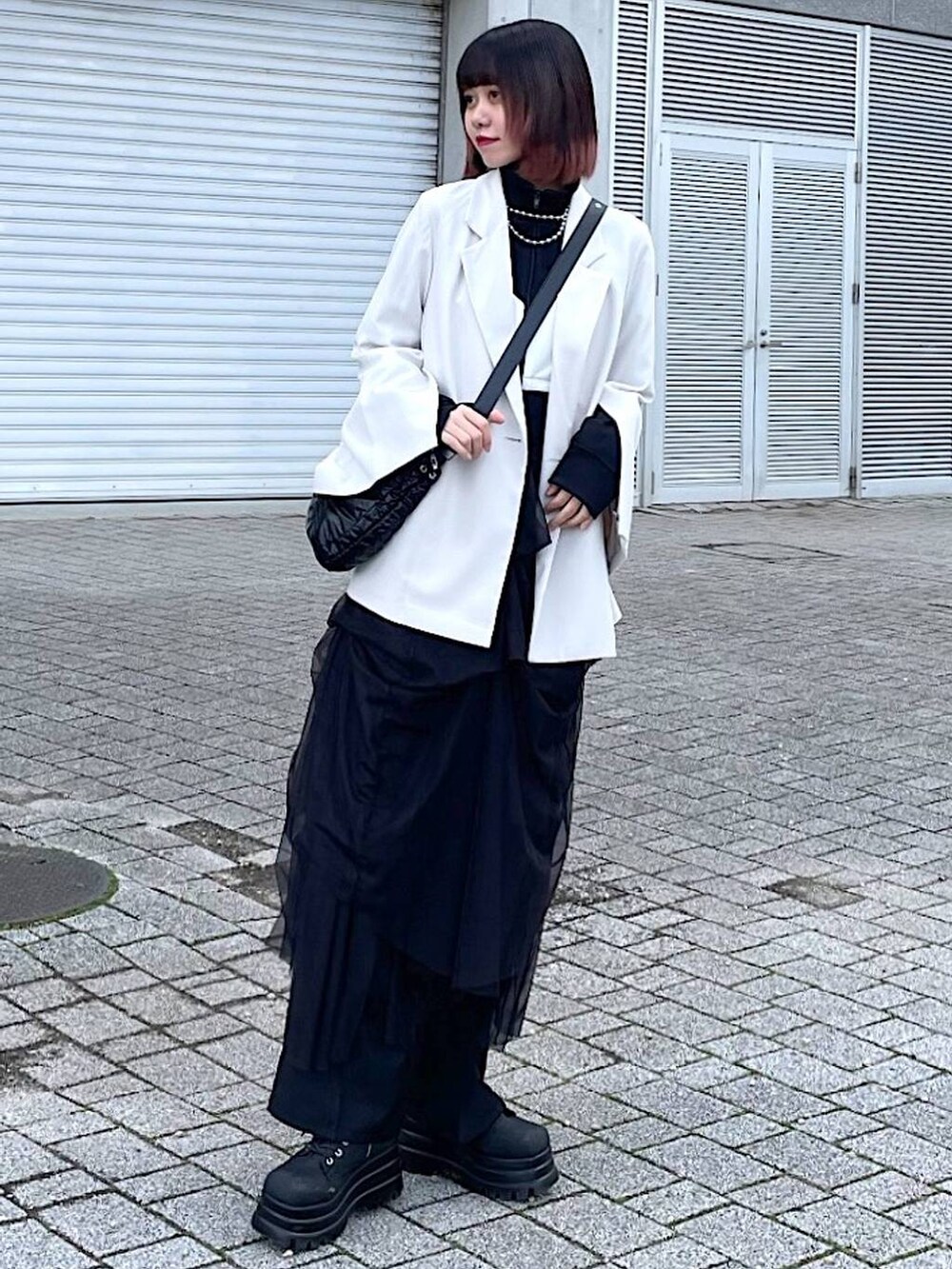 ブラック系のショルダーバッグ、ブラック系のナイロンジャケット、ブラック系のスカートを着用したレディースの春コーディネートの4枚目の写真