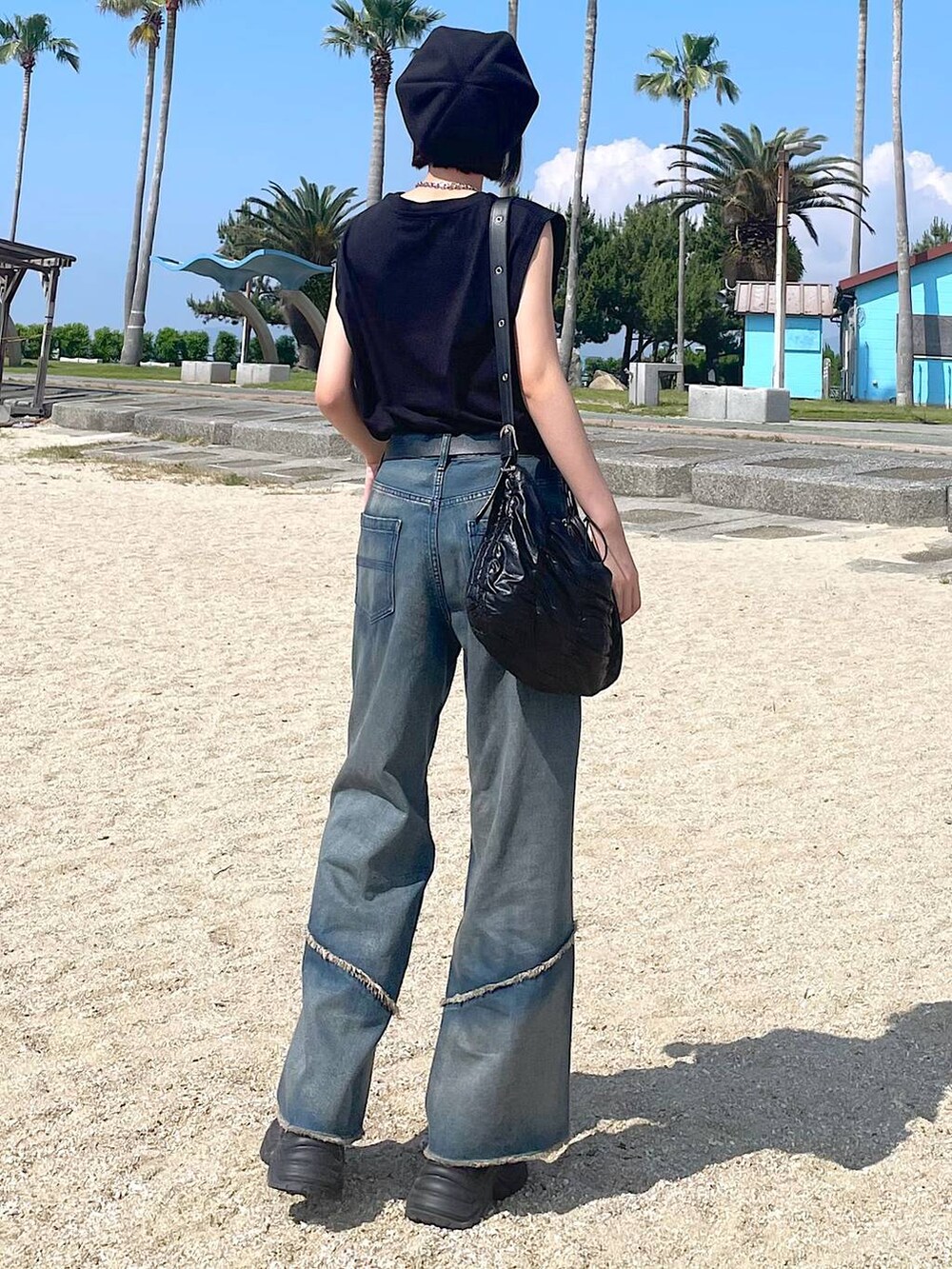 ブラック系のショルダーバッグ、ブラック系のスニーカー、オレンジ系のデニムパンツを着用したレディースの夏コーディネートの3枚目の写真