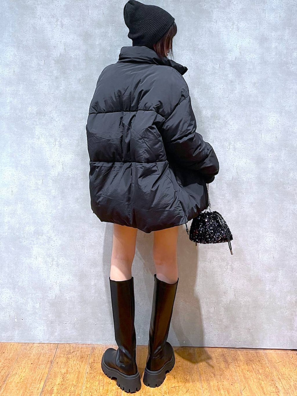 グレー系のスカート、ブラック系のブーツ、ブラック系のダウンジャケット/コートを着用したレディースの冬コーディネートの3枚目の写真