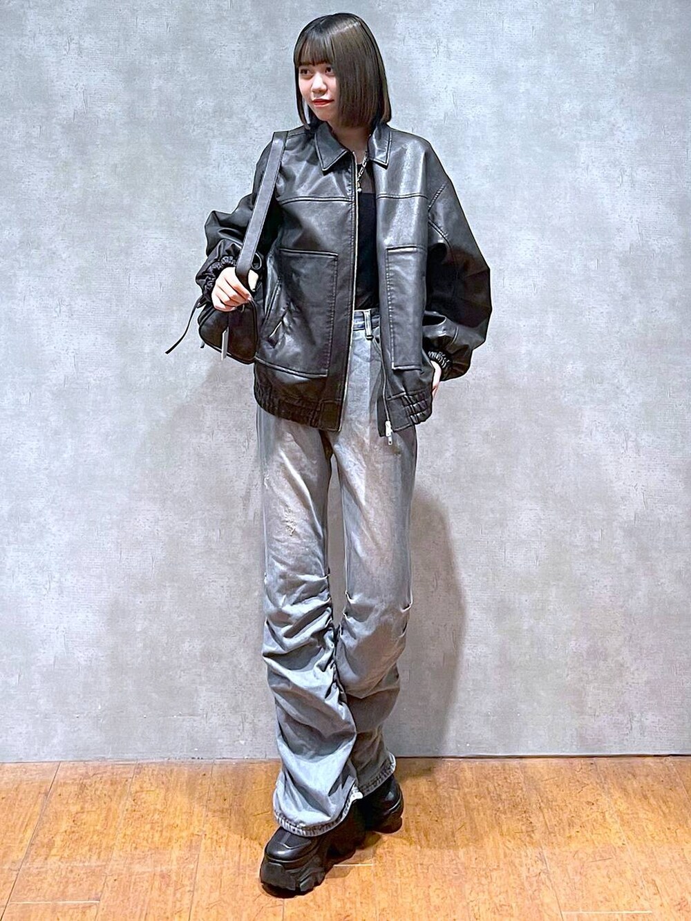 ブラック系のスニーカー、ブラック系のショルダーバッグ、ブルー系のデニムパンツを着用したレディースの秋コーディネートの4枚目の写真