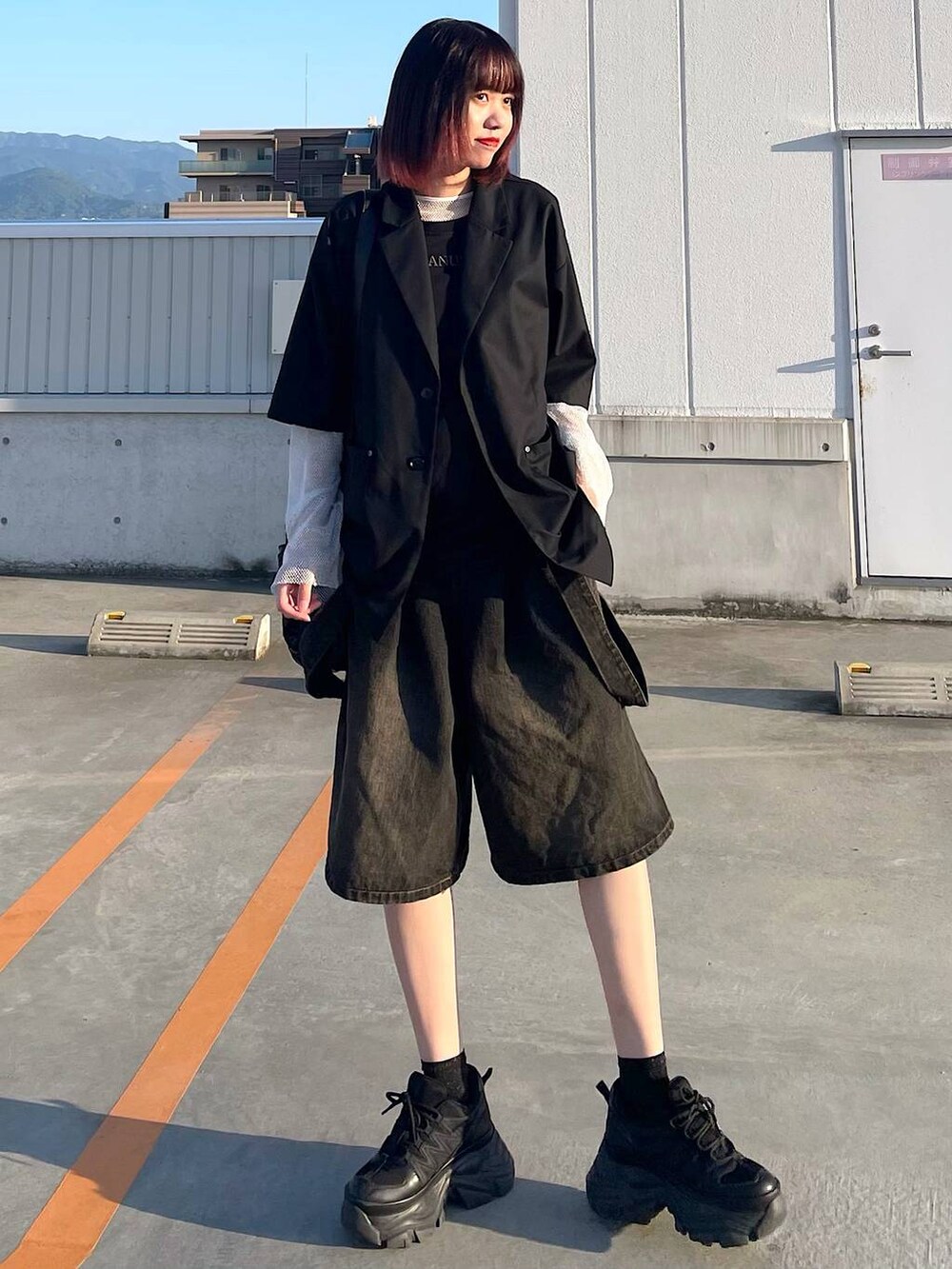 ブラック系のショルダーバッグ、ブラック系のスニーカー、ホワイト系のTシャツ/カットソーを着用したレディースの春コーディネートの2枚目の写真